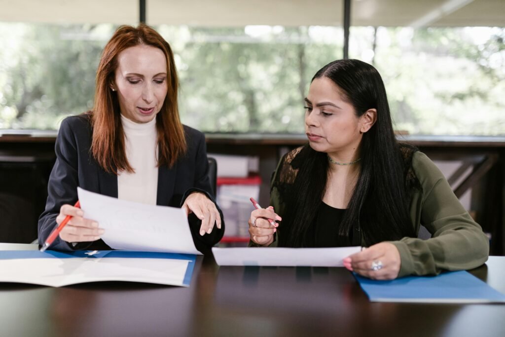 Two professional women reviewing documents in a well-lit office setting.